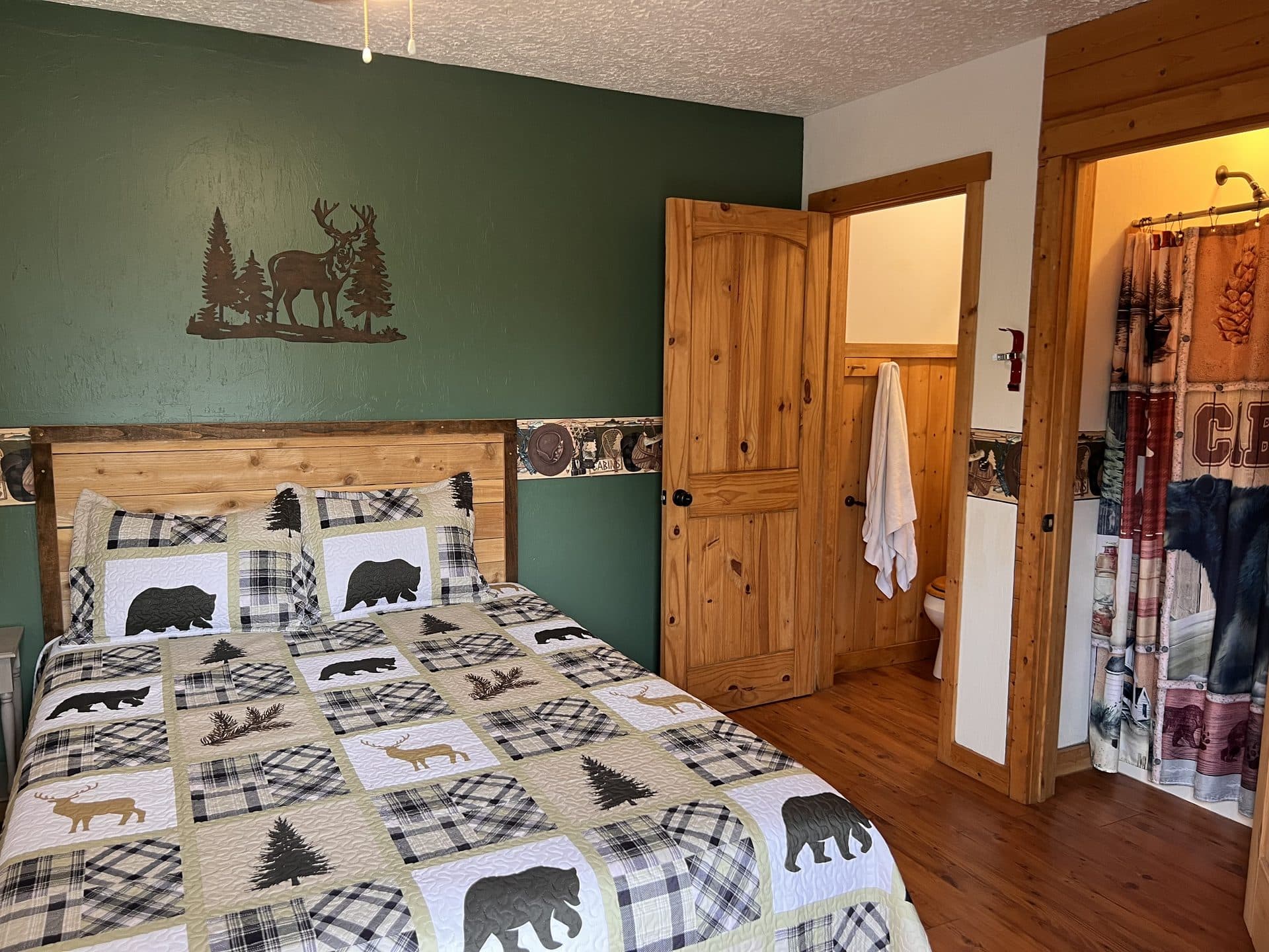Cabin bedroom with forest green accent wall and deer decor