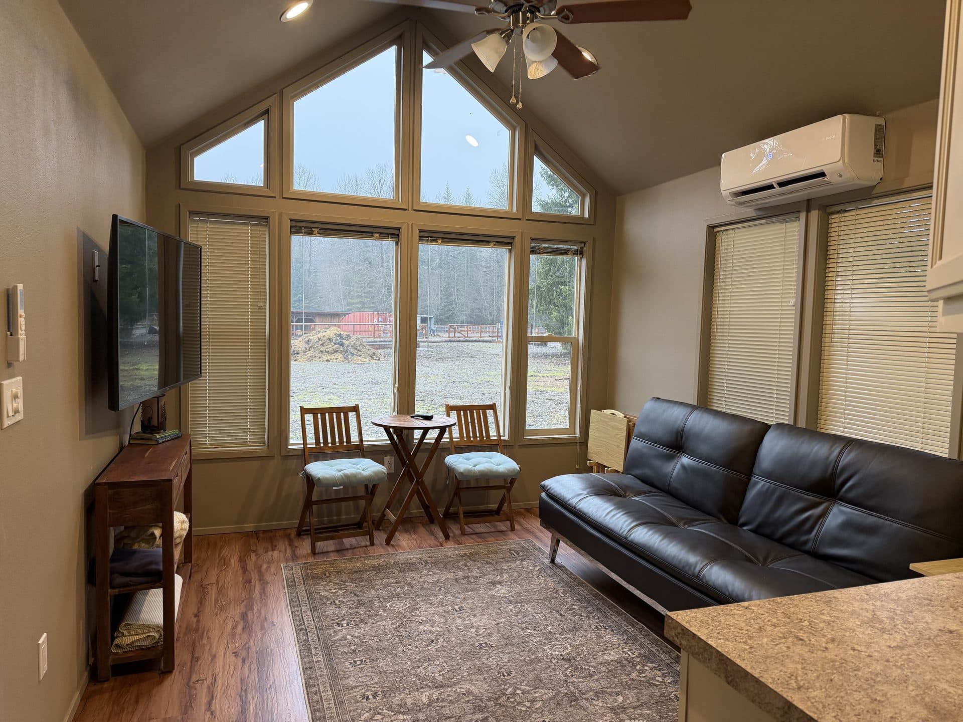Tiny home living room with floor-to-ceiling A-frame windows and hardwood floors